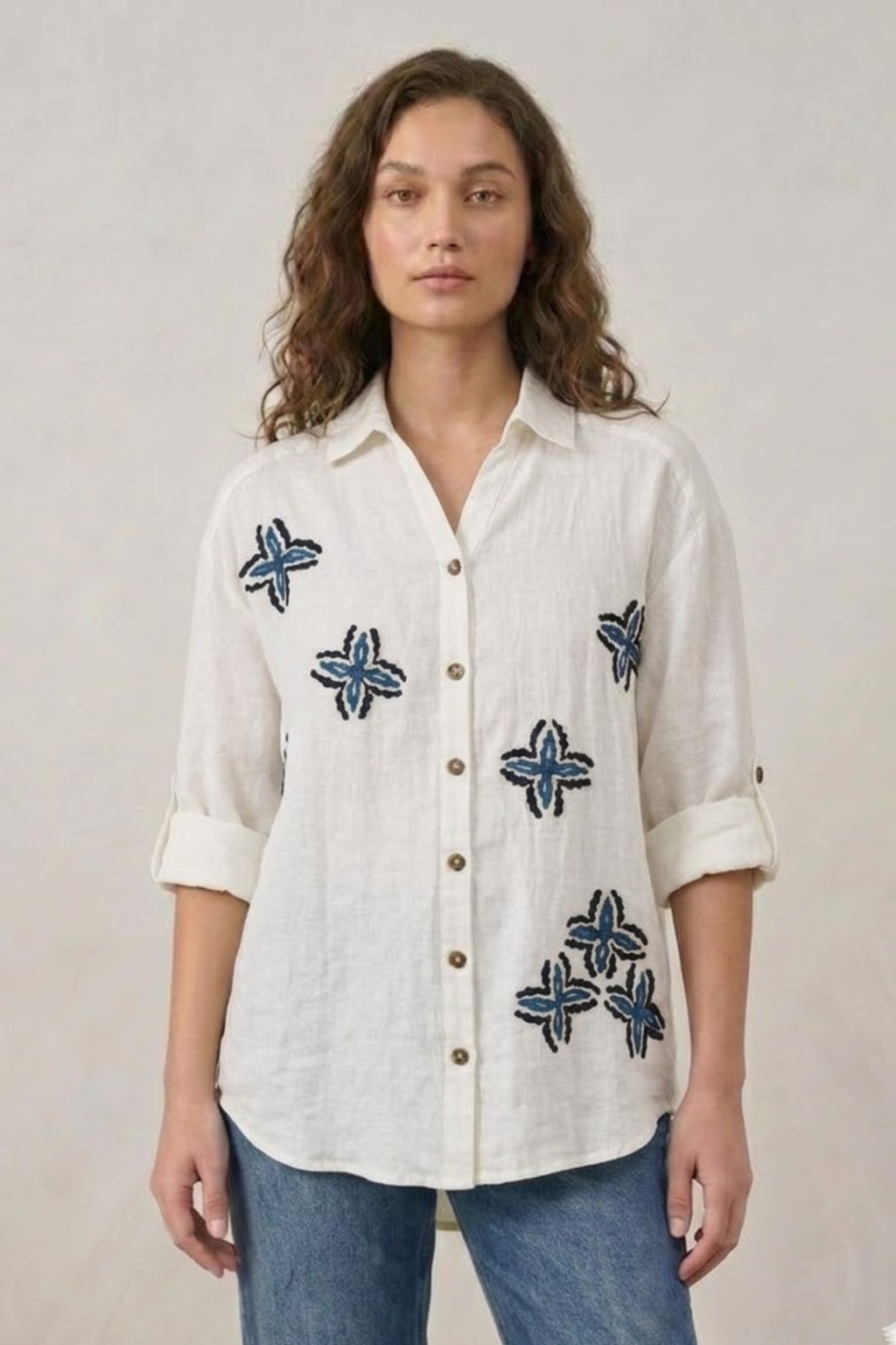 Woman wearing a white shirt with blue floral patterns on a plain background