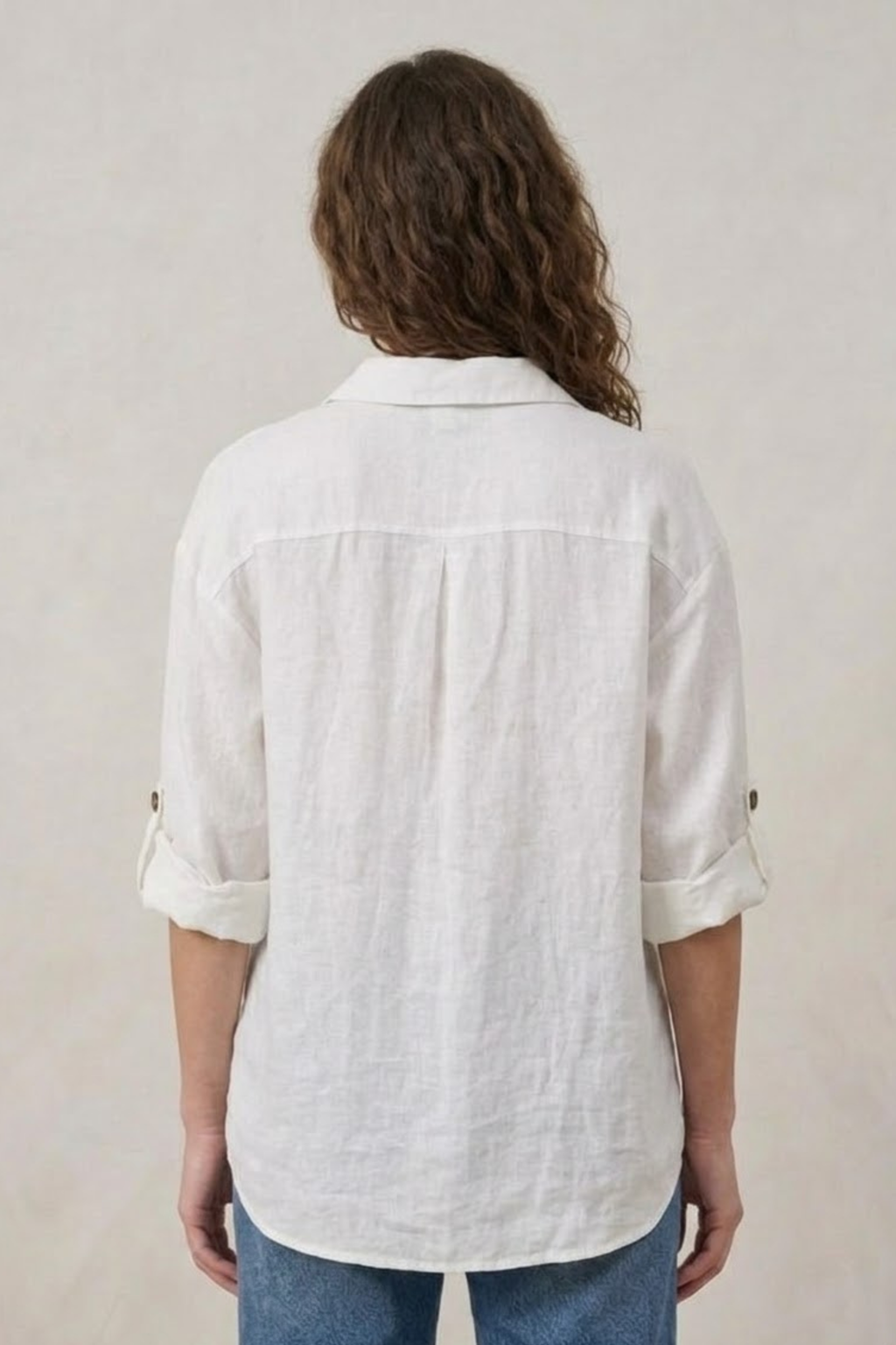 Person wearing a white textured shirt with rolled-up sleeves on a plain background