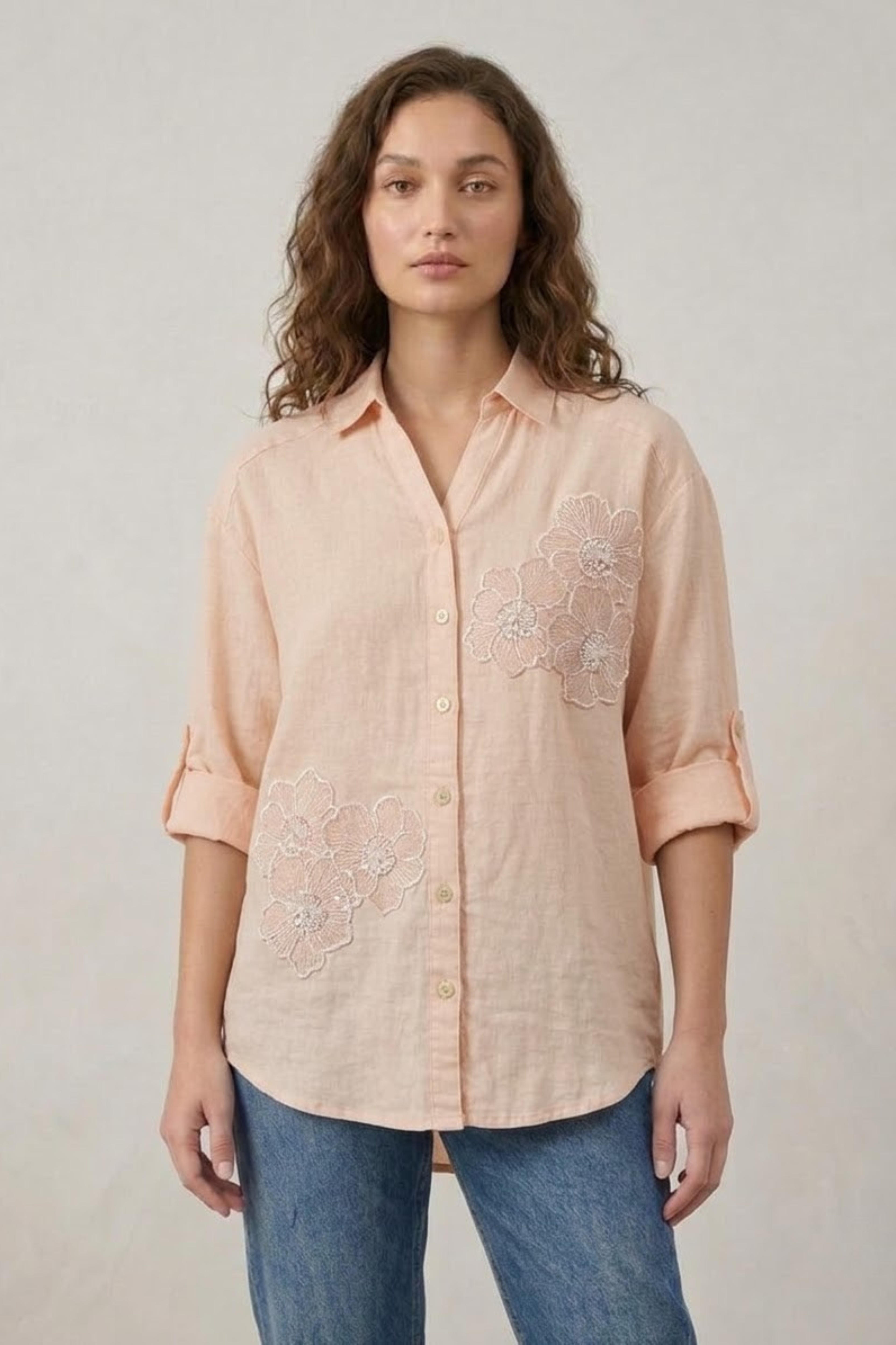 Close-up of a women's light pink 100% linen shirt featuring intricate white floral embroidery and a versatile "wear it either way" reversible design.