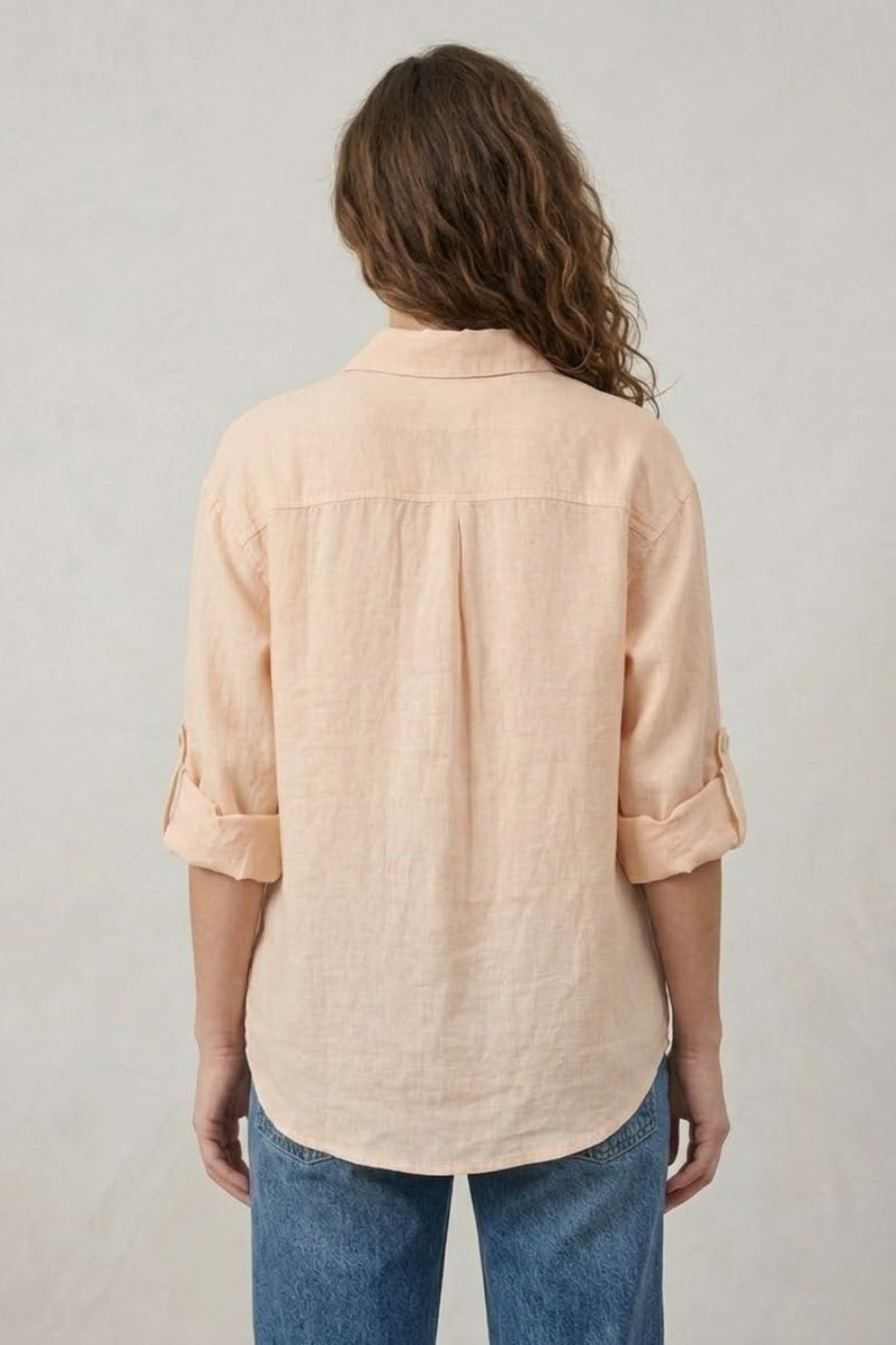 Close-up of a women's light pink 100% linen shirt featuring intricate white floral embroidery and a versatile "wear it either way" reversible design.