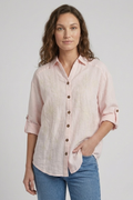Woman wearing a light pink button-up shirt and blue jeans on a plain background