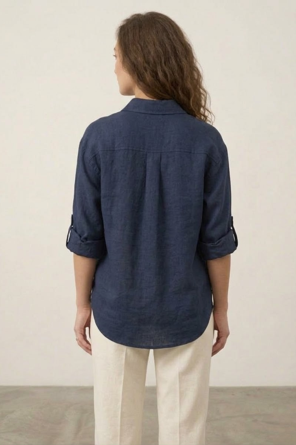 Person wearing a navy blue shirt and beige pants against a plain background