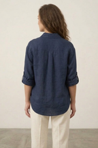 Person wearing a navy blue shirt and beige pants against a plain background