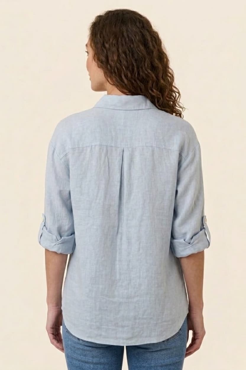 Woman wearing a light blue button-up shirt with rolled-up sleeves on a beige background